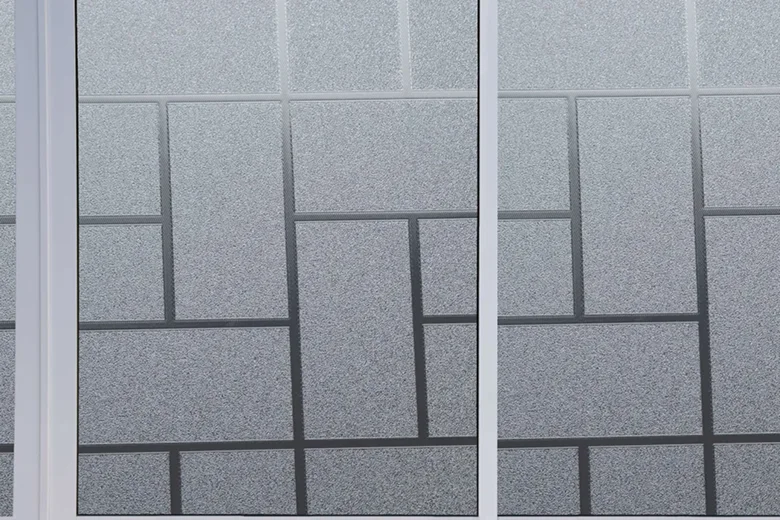 Close-up of frosted window film with a geometric block pattern, applied to three adjacent glass panes for added privacy.