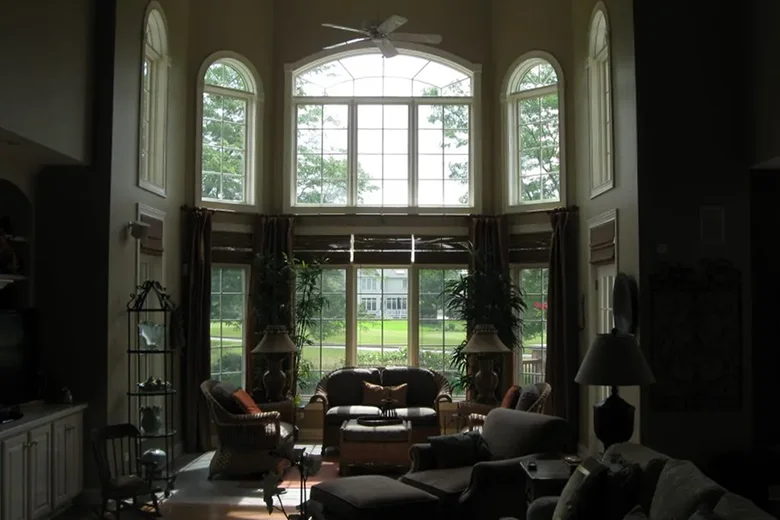 Spacious living room with high ceilings and large, arched windows allowing natural light to illuminate the cozy seating area.