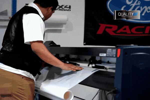A technician at a Gulfport shop uses a digital plotter to cut Paint Protection Film with precision, ensuring an exact fit for vehicle panels as part of expert professional installation, highlighting the importance of accuracy when learning what is paint protection film.
