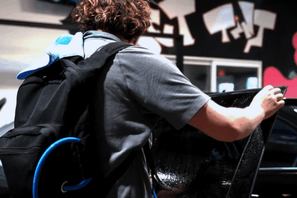 Quality Tint & Accessories expert applying window tint film to a car door inside the shop.