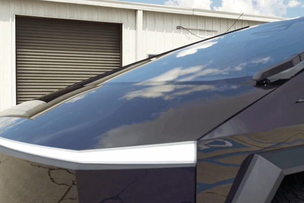 Close-up of a futuristic vehicle with sleek, dark-tinted windows under clear skies.