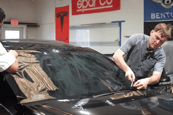 Quality Tint & Accessories experts installing window tint film on a car windshield for improved privacy and security.