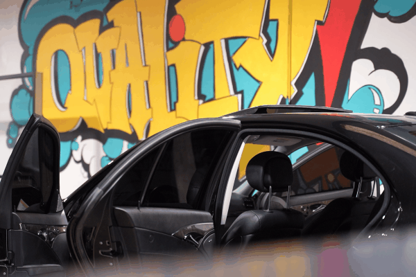 Black Mercedes sedan receiving professional window tint installation inside the Quality Tint & Accessories workshop.