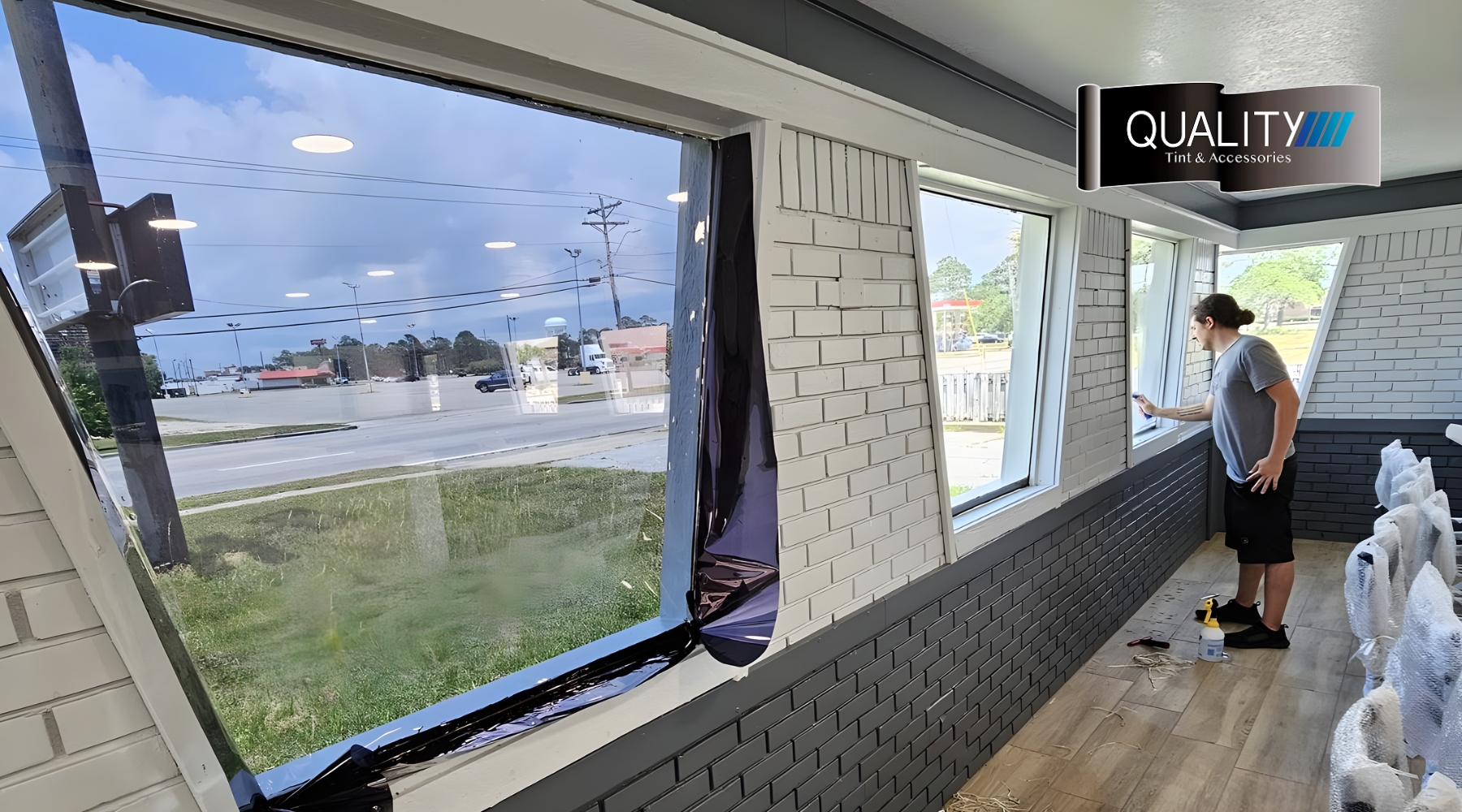 Close-up of residential window tinting in progress on large street-facing windows in Gulfport, MS. A technician smooths the film onto the glass, demonstrating what is residential window tinting and how it helps control heat and UV exposure in sunny climates.
