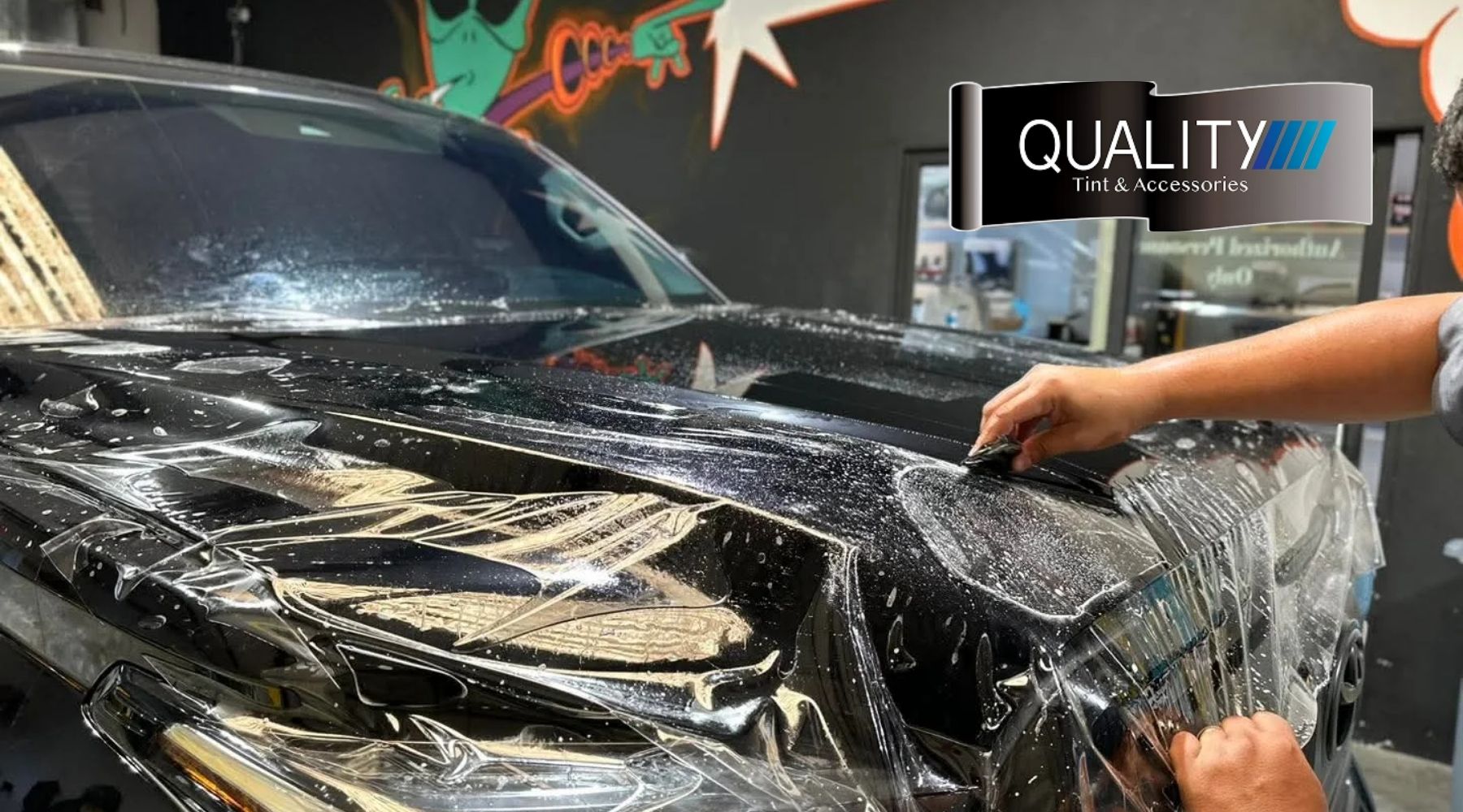 Professional installation of paint protection film (PPF) on a black vehicle at Quality Tint & Accessories.