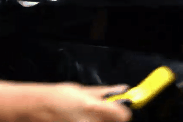 Close-up of a hand inspecting a smooth, freshly applied paint protection film on a black car surface.