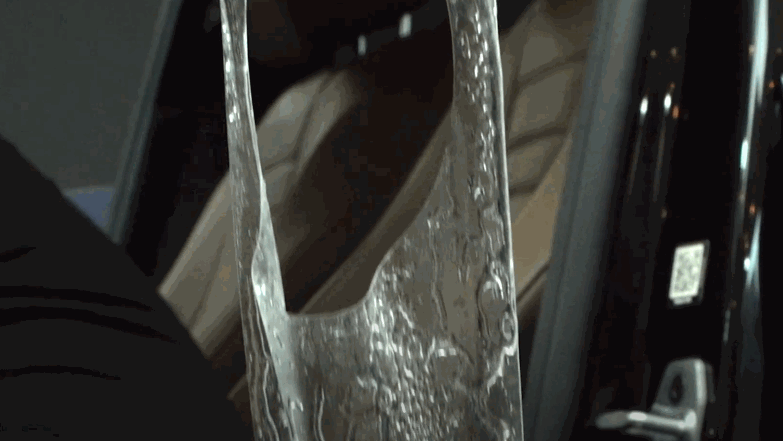 A close-up view of clear paint protection film being applied to the edge of a car door, with visible water and air bubbles being smoothed out.