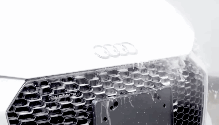Water beads and runs off the front grille and hood of a white Audi, demonstrating the hydrophobic effect of ceramic coating.