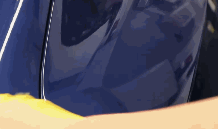 A yellow microfiber cloth is used to buff a blue car panel after a ceramic coating application, revealing a deep, mirror-like finish.